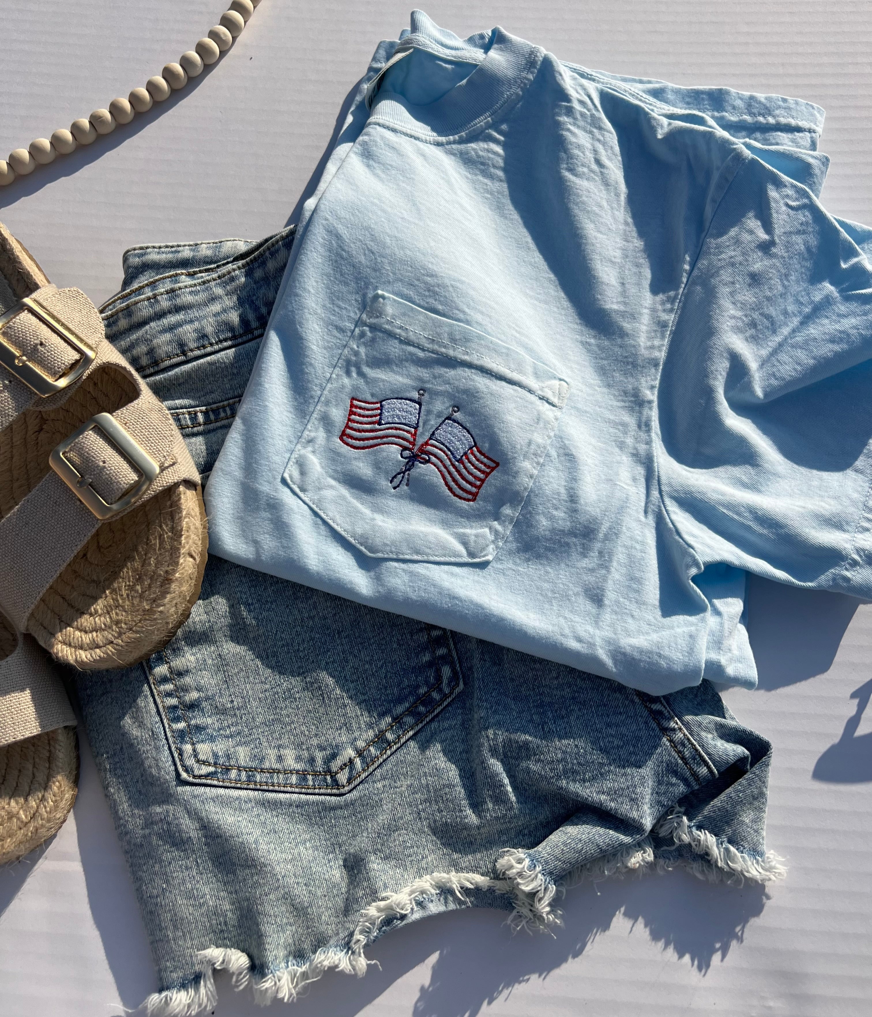 light blue tshirt with a pocket embroidered with american flags and a bow