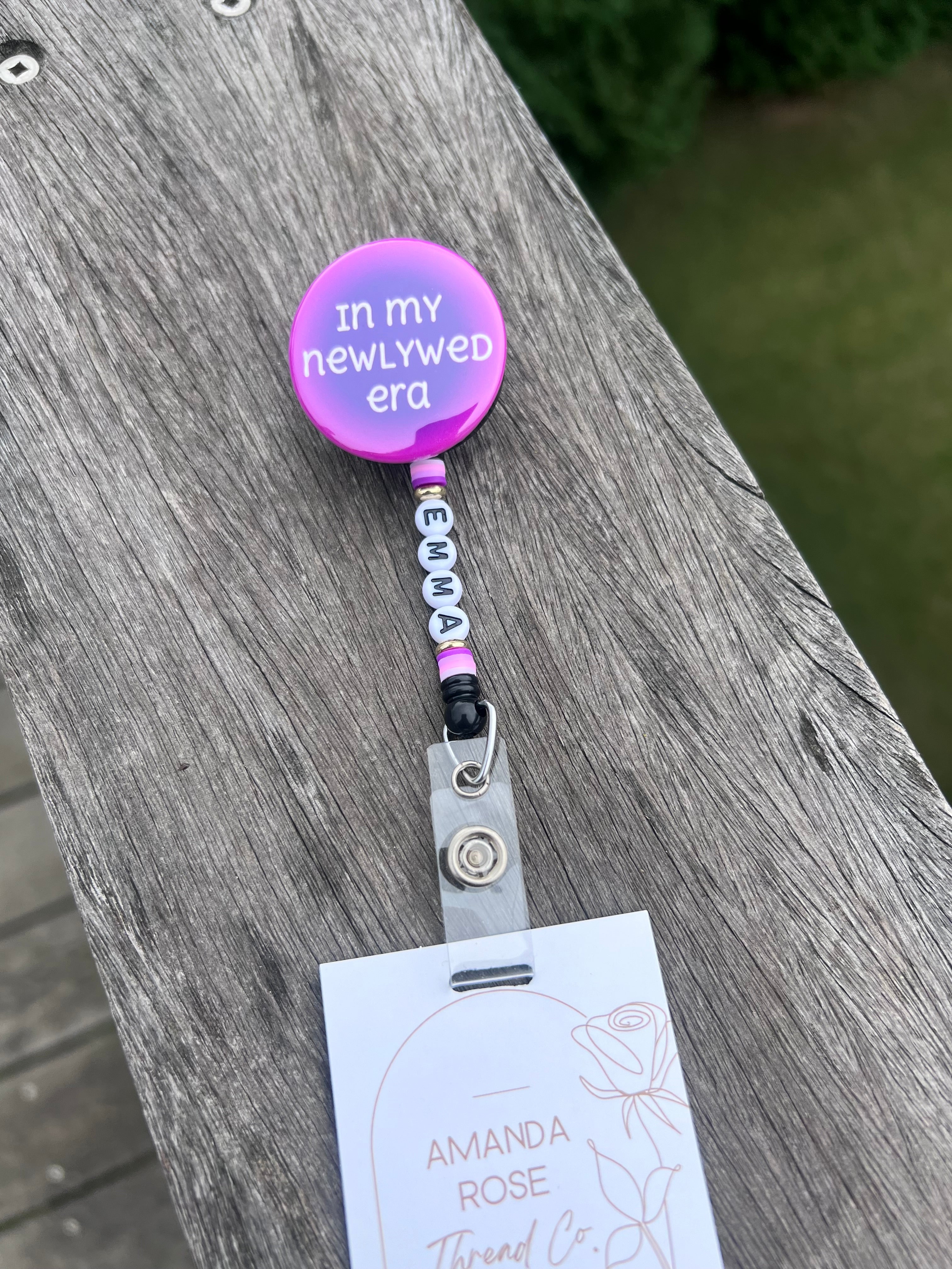 button badge holder with in my newlywed era written on it, with name on beads on badge reel string