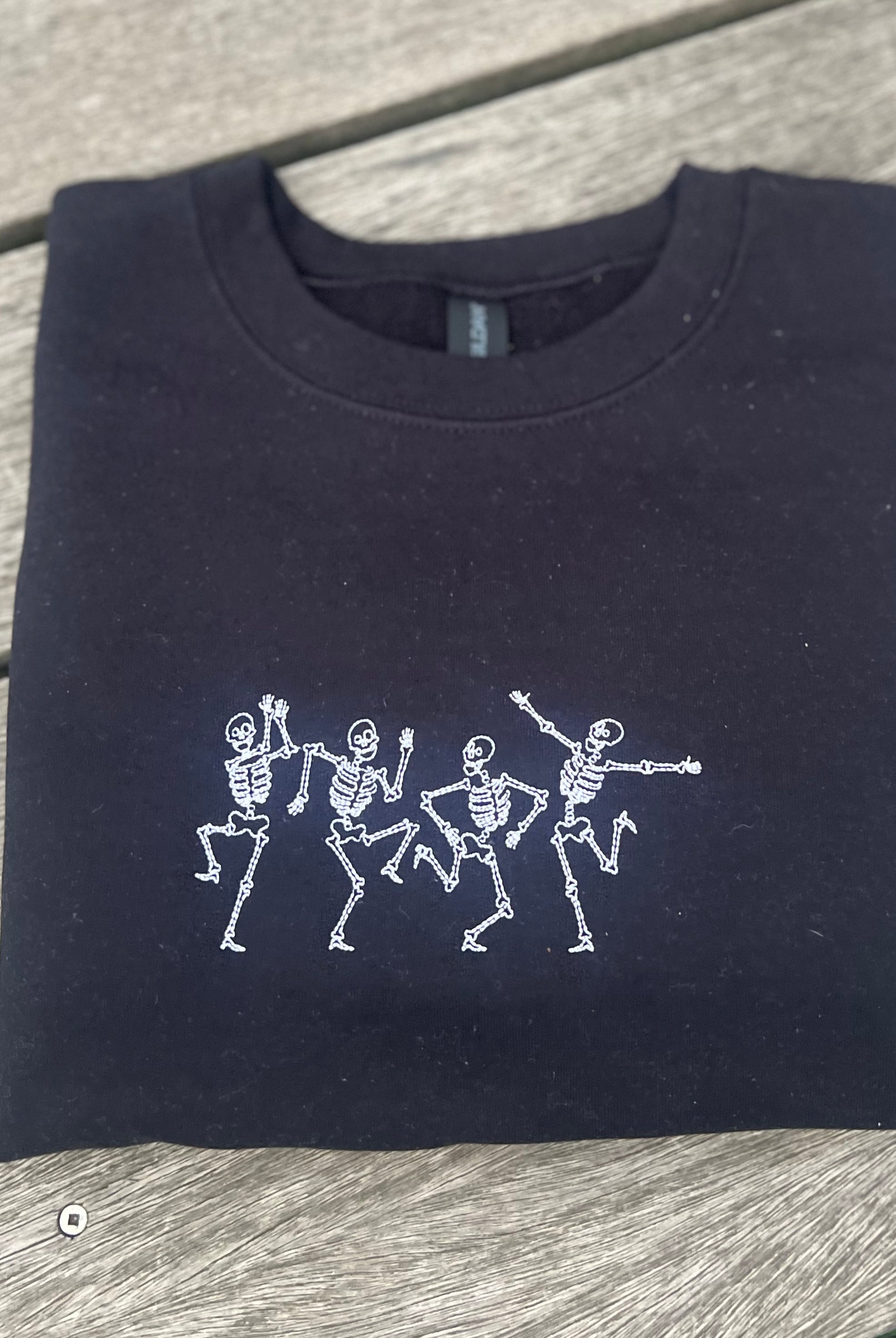 Black sweatshirt with embroidered white skeleton dancing design