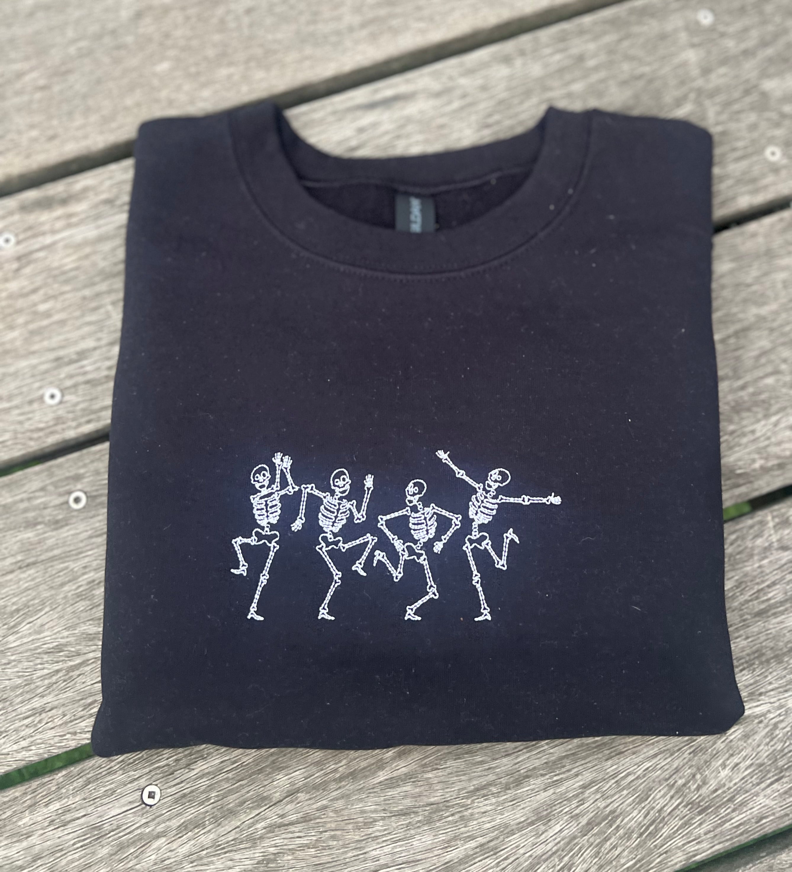Black sweatshirt with embroidered white skeleton dancing design