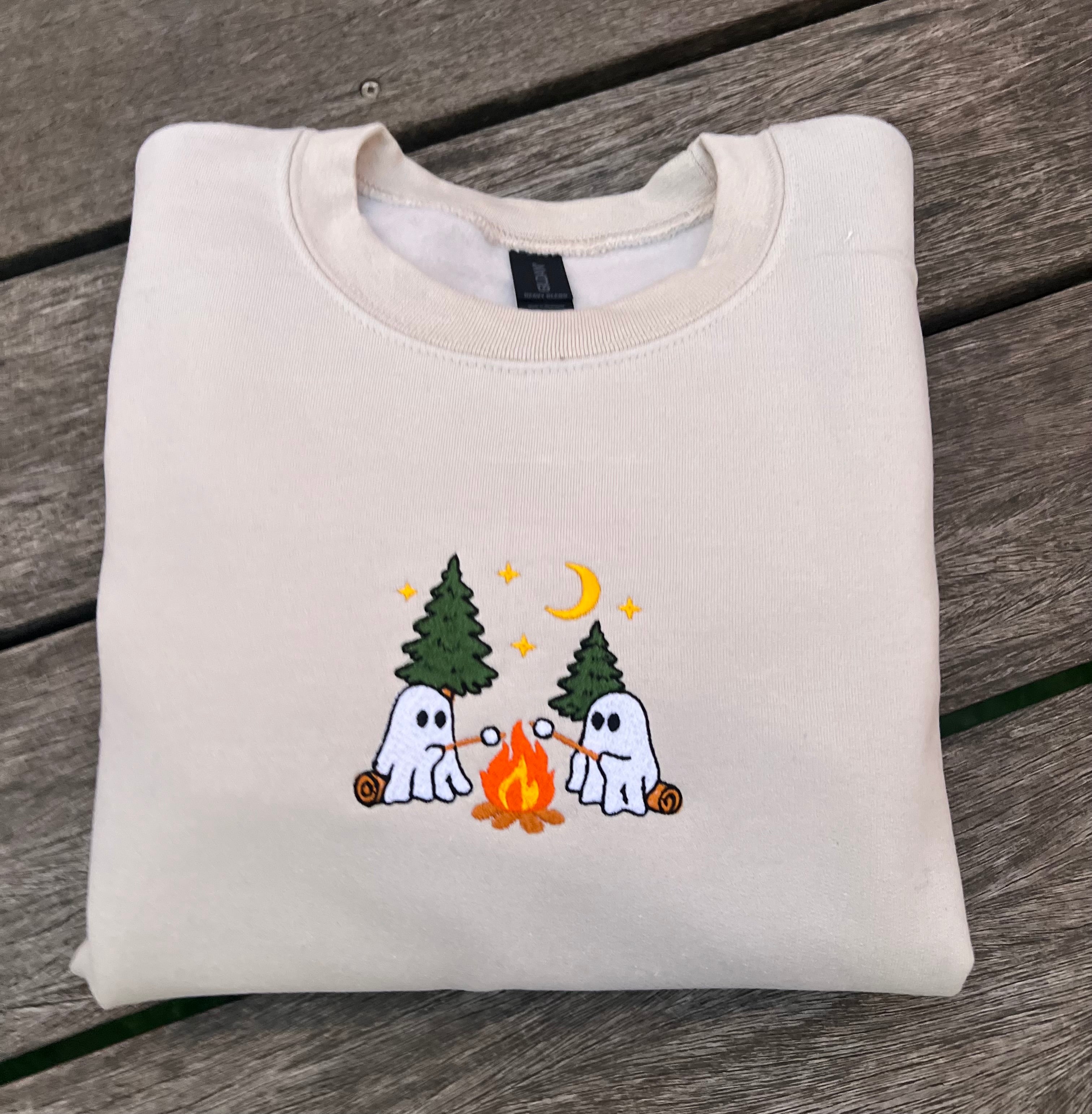 embroidered ghosts roasting smores at campfire on a neutral sweatshirt