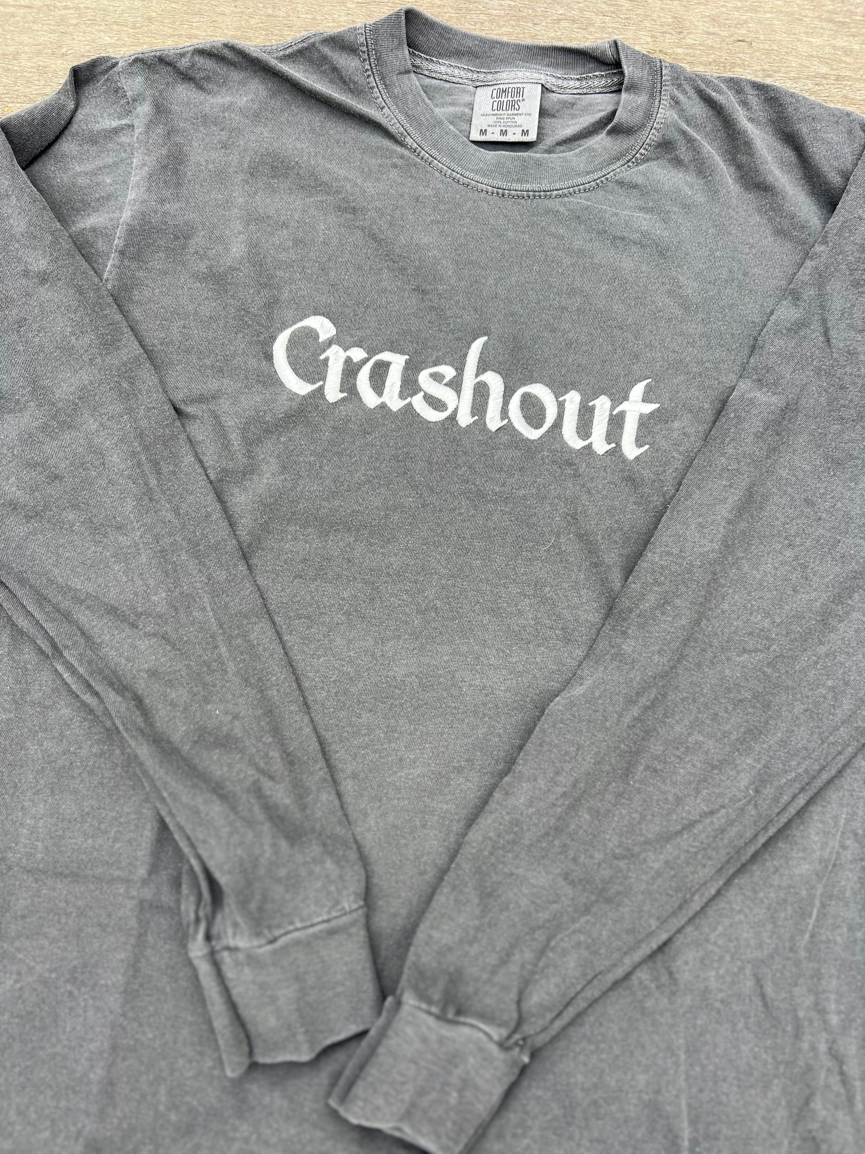 Gray long-sleeve shirt with 'Crashout' text on a plain background