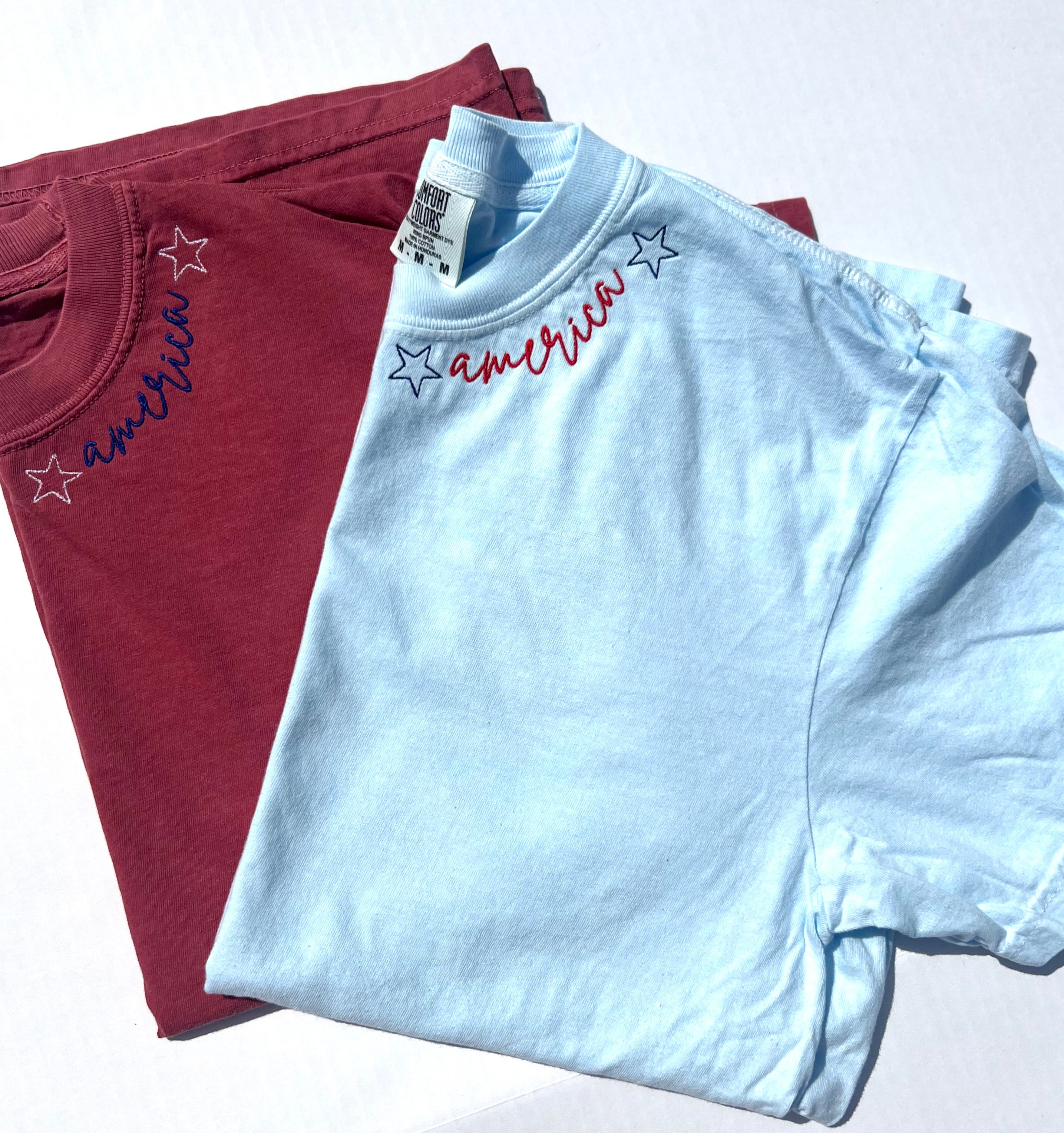 Two folded t-shirts with 'America' text and star designs on a white background