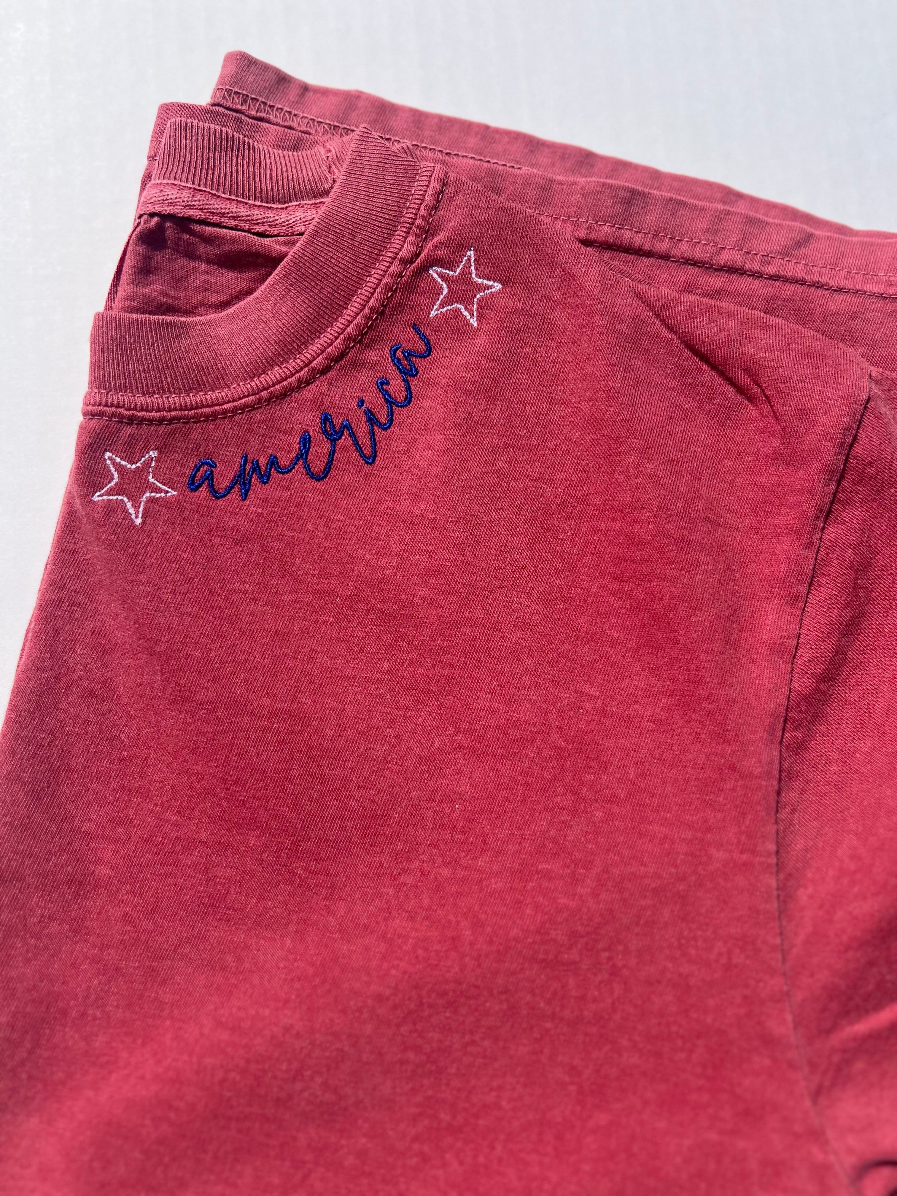 Red sweatshirt with 'america' text and star designs on a light gray background
