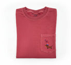 Folded red shirt with a patriotic dachsund eating a hotdog on a pocket design on a white surface