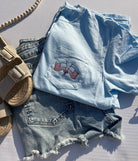 light blue tshirt with a pocket embroidered with american flags and a bow