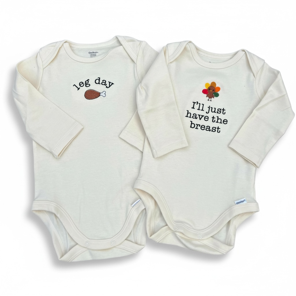 Two white baby onesies with humorous text and graphics on a white background