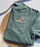 green t-shirt with a pocket with a cat embroidered onto it, peeking out of the pocket