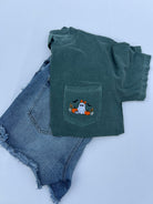 A dark green short-sleeve t-shirt with a front pocket featuring a cute embroidered ghost and pumpkin designbackground.
