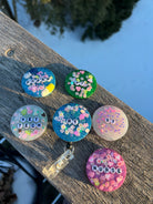 Colorful badge reels with various designs on a wooden surface