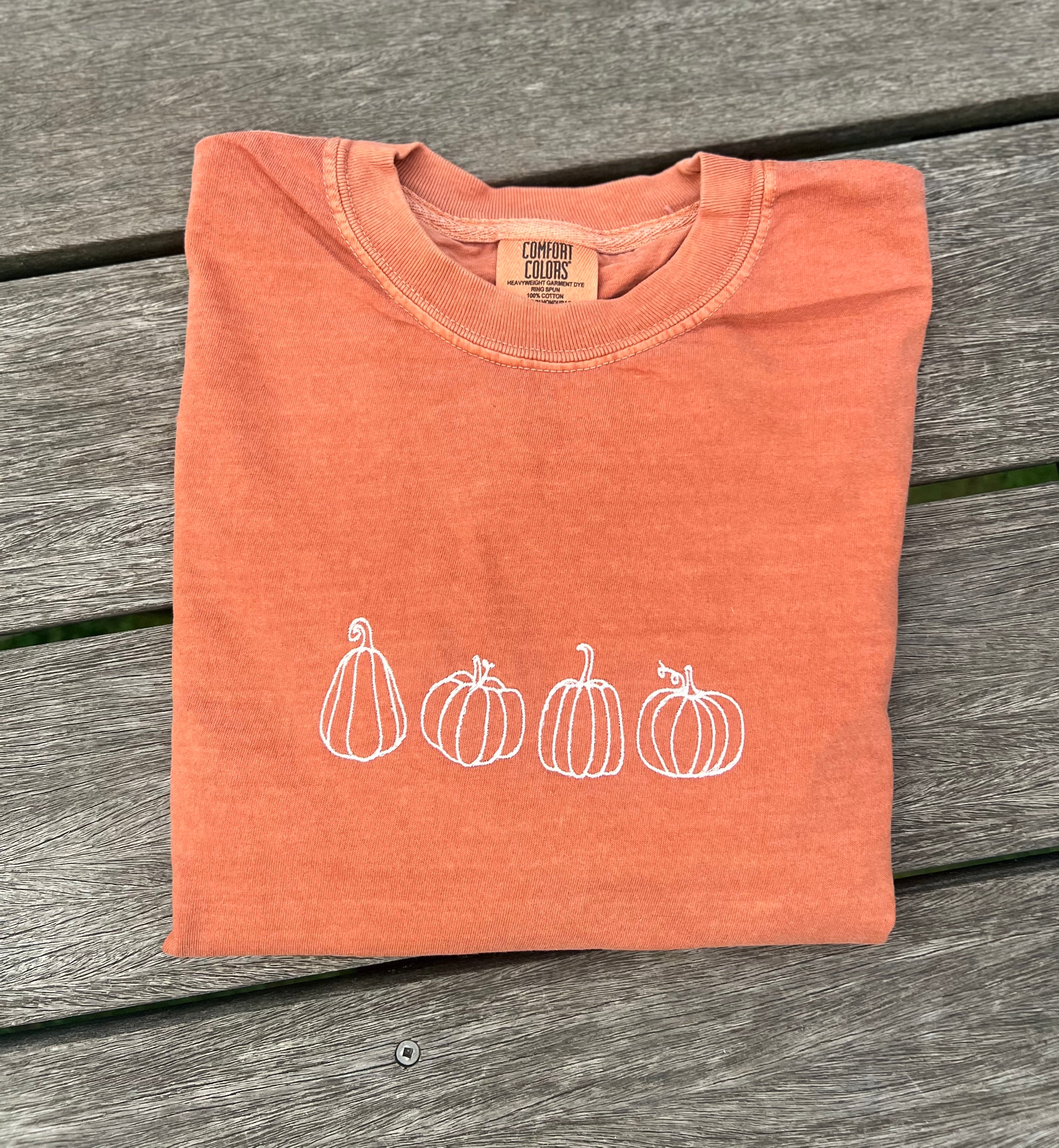 orange long sleeve shirt with embroidered white pumpkins