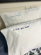 Two white pillows with I love you more and sweet dreams embroidered on them