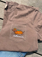 A brown pocket t-shirt with a graphic of a dachshund wearing an orange pumpkin hat and the text 'Halloweenie' on the front pocket.