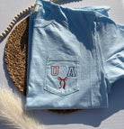 Folded light blue t-shirt with 'USA'  and  a red bow embroidery 