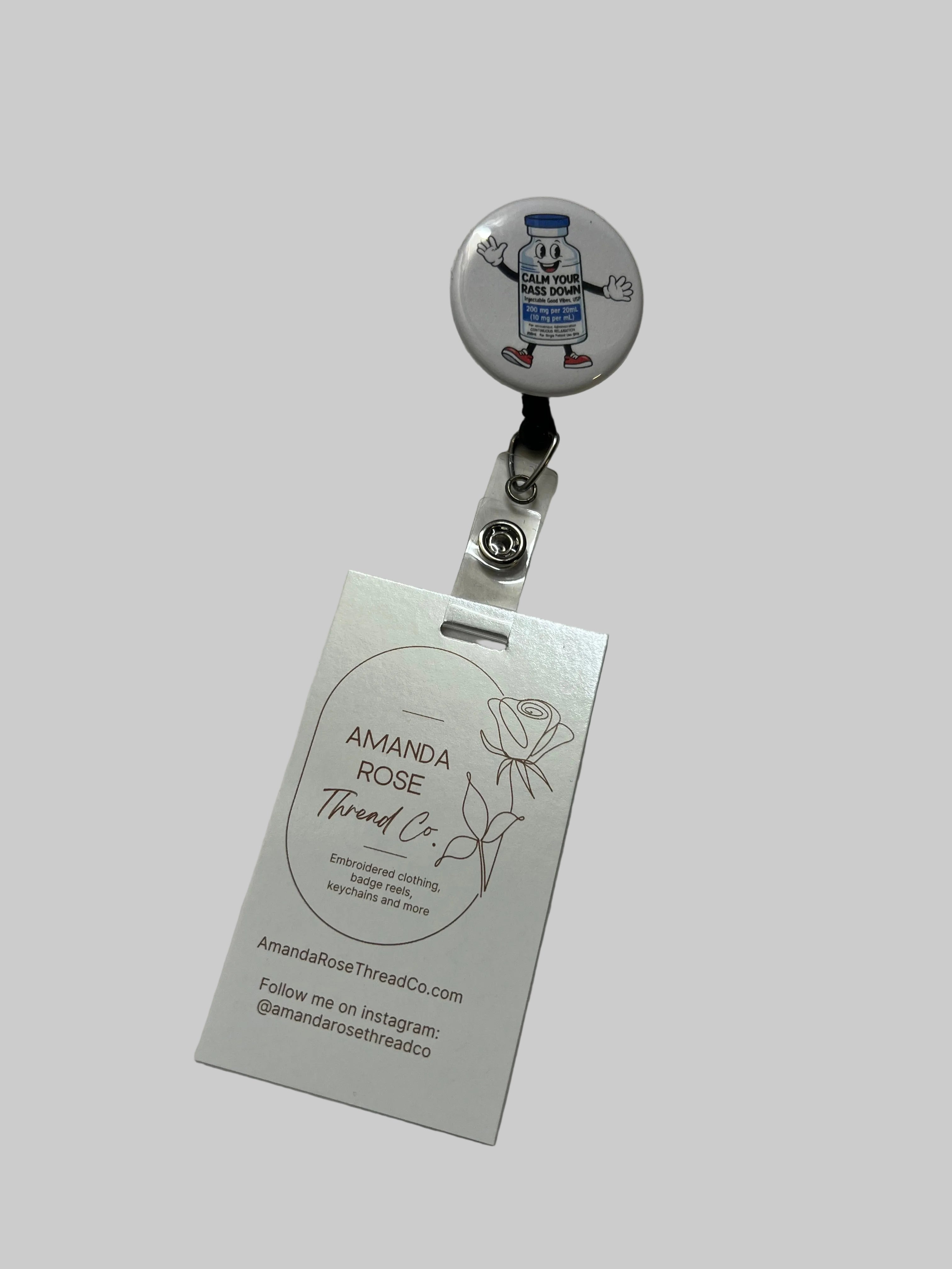 Badge holder with a round emblem and a business card on a light gray background