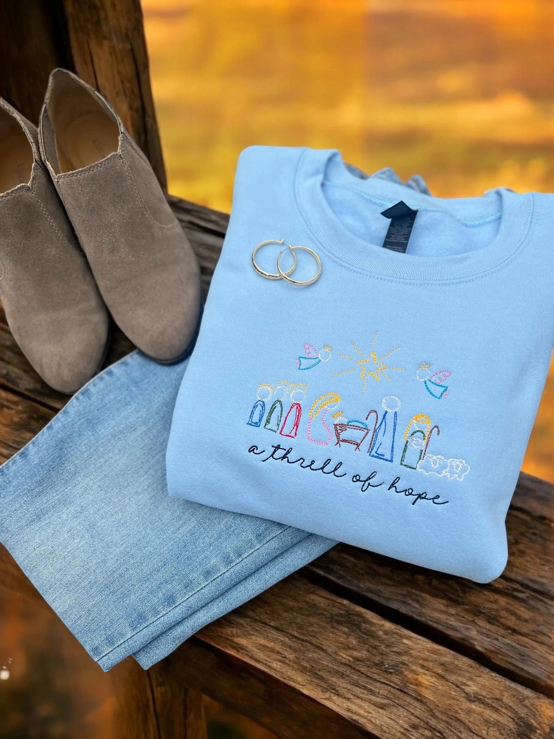 Light blue sweatshirt with embroidered nativity scene for christmas.