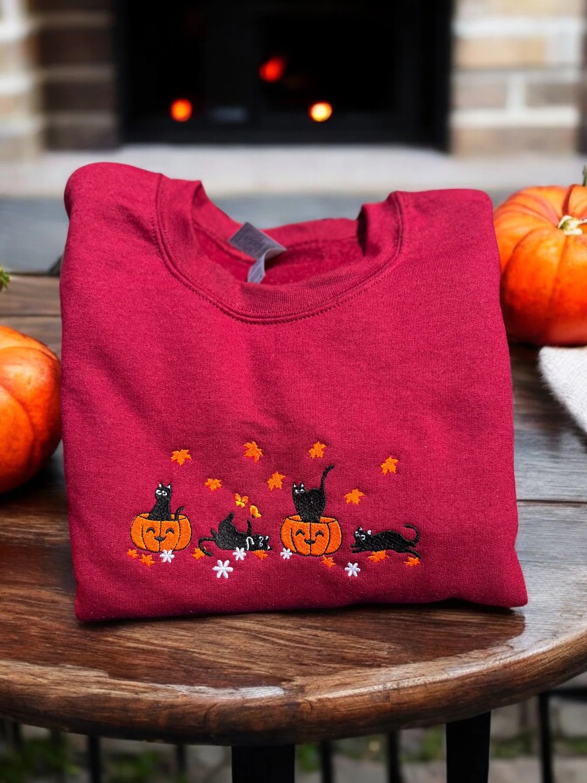 Red sweatshirt with Halloween embroidered design of black cats and pumpkins