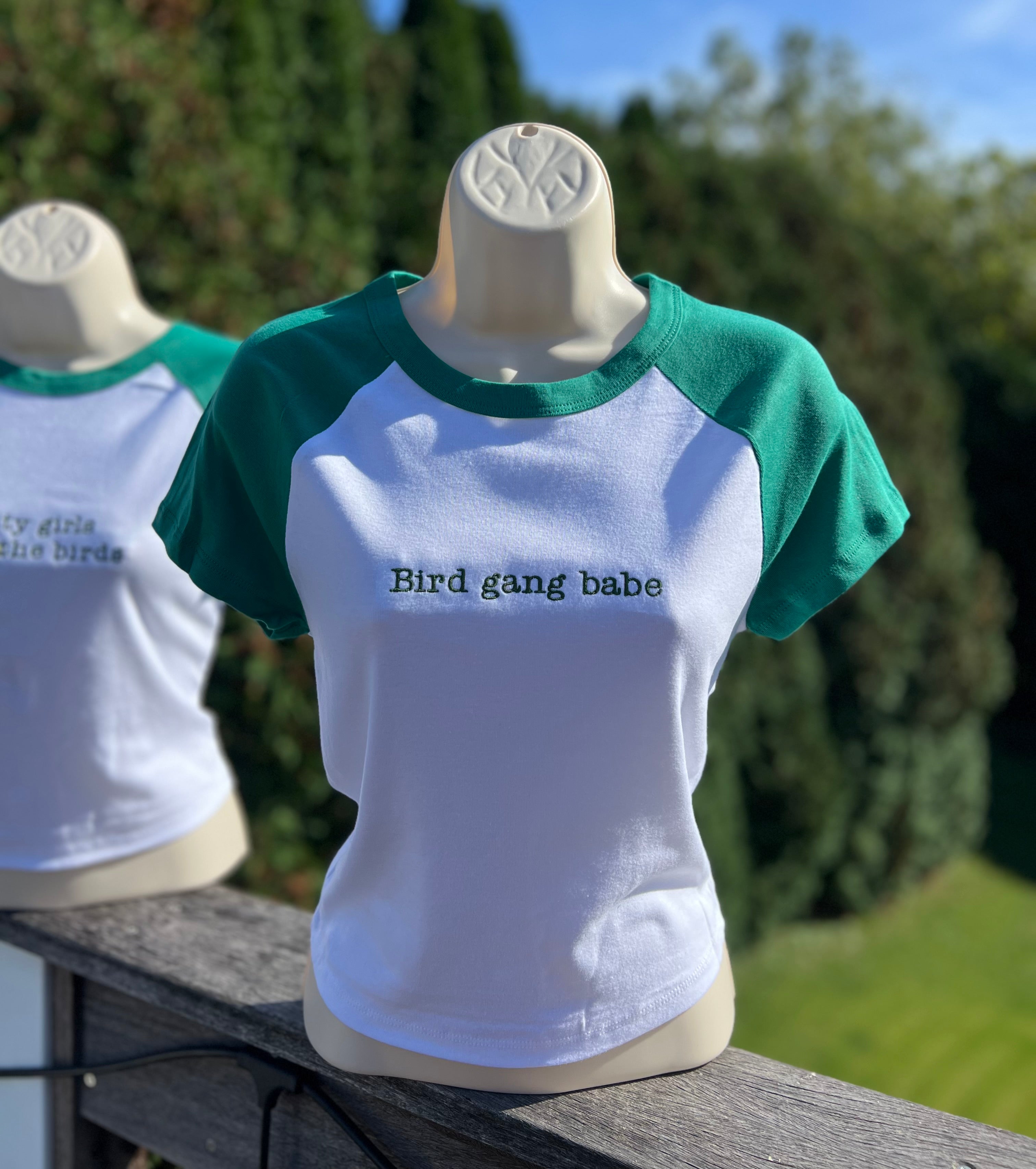 White cropped t-shirt with green sleeves and 'Bird gang babe' embroidered on it